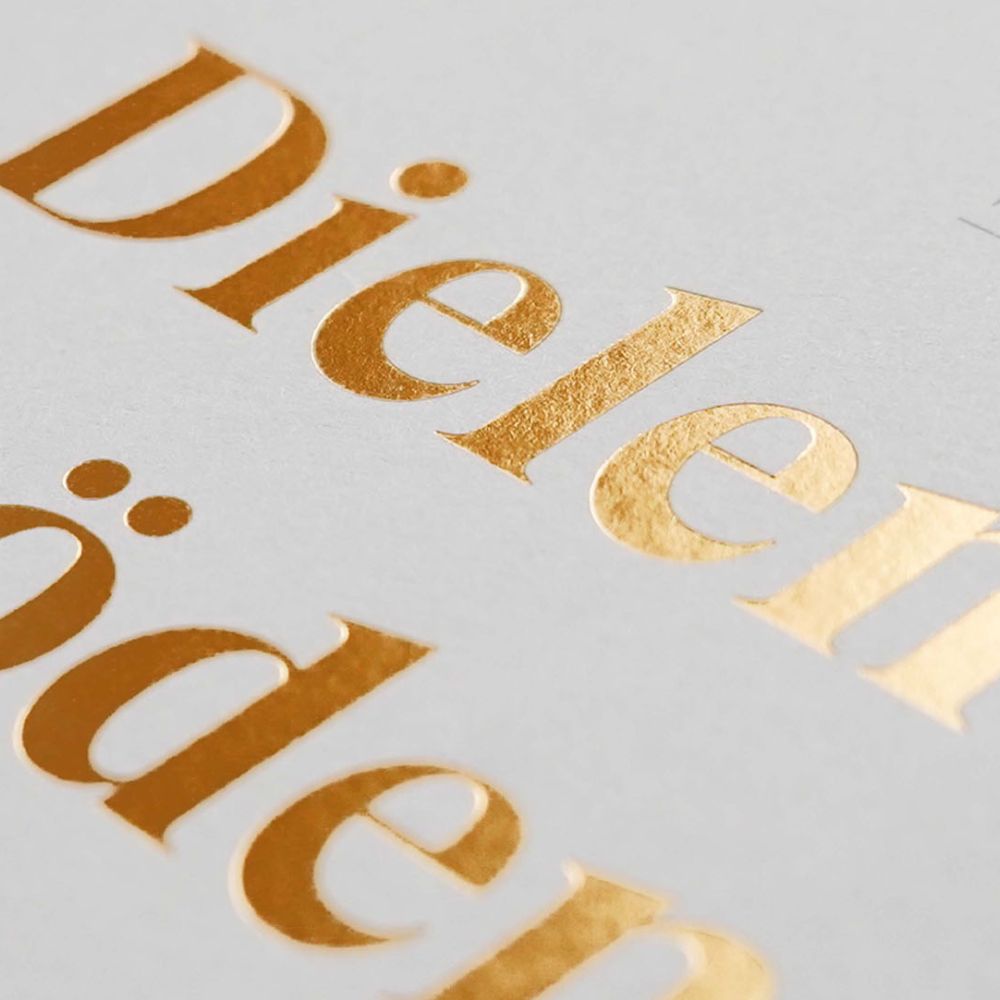 Nahaufnahme eines hochwertigen Produktkatalogs mit goldglänzendem Schriftzug „Dielenböden“ auf weißem Cover