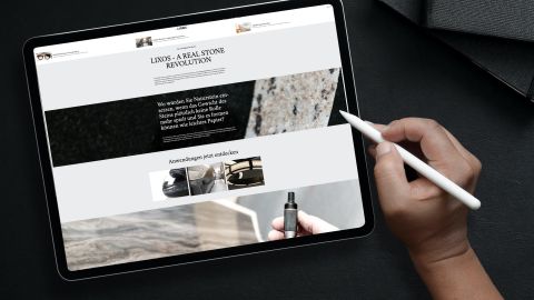 LIXOS Website auf iPad Hand mit Stylus vor Tablet, das eine Website über leichtes Natursteinfurnier und dessen Anwendungen zeigt.