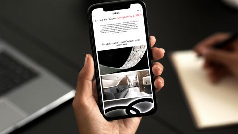 LIXOS Website auf iPhone Smartphone zeigt LIXOS-Website mit Natursteinfurnier-Produkten und modernen Anwendungsbeispielen im Interior Design.