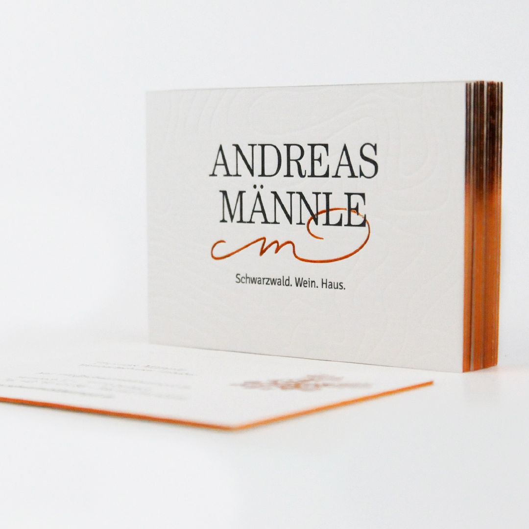 Andreas Männle Visitenkarten Ein Stapel weißer Visitenkarten mit kupferfarbenem Rand und der Aufschrift "Andreas Männle" in schwarz.