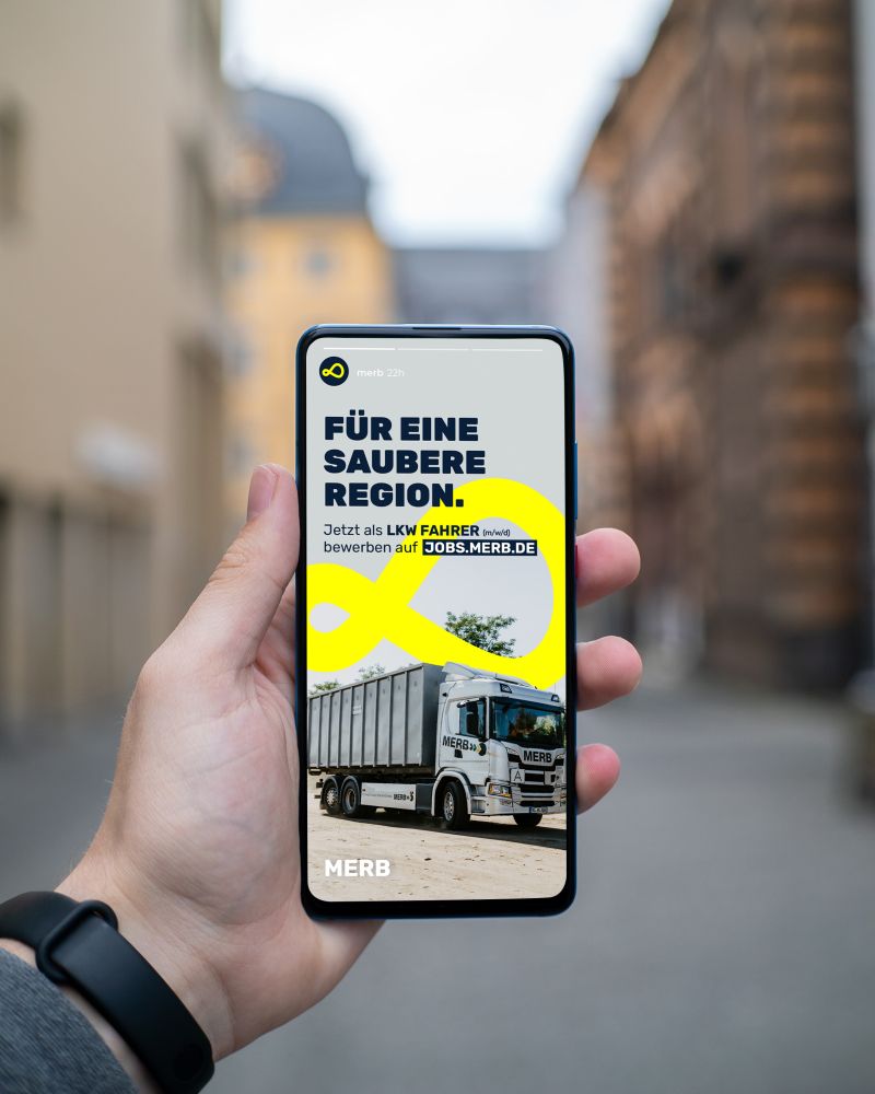 Eine Hand, die ein Smartphone hält, zeigt eine Stellenanzeige für Lkw-Fahrer.